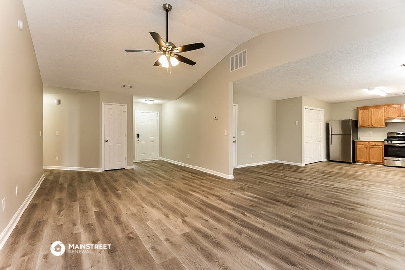 an empty living room and kitchen with a ceiling fan