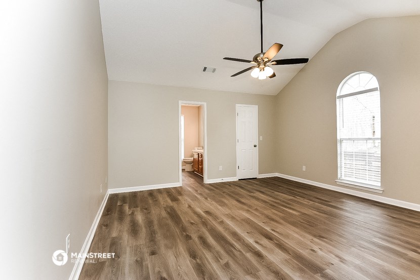 an empty living room with wood floors and a ceiling fan