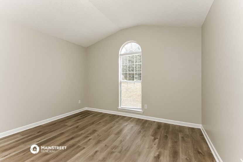 an empty living room with a large window and wooden floors