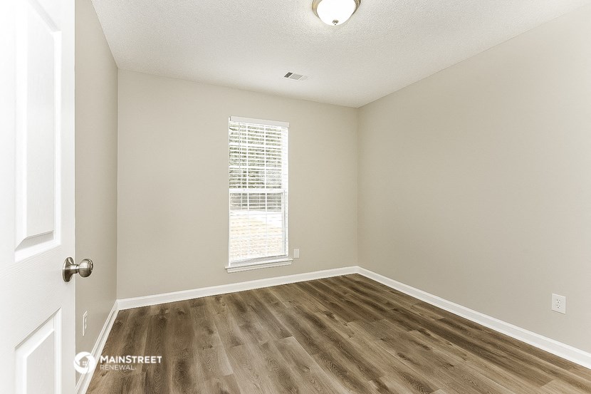 an empty room with a window and wood floors