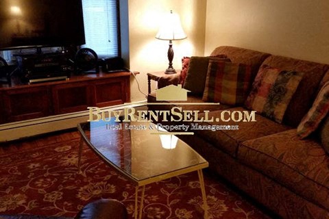 A living room with a BuyRentSell.com sign on the coffee table.