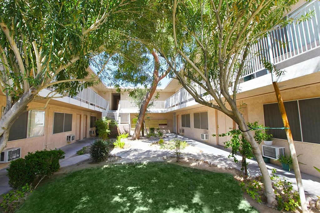 the courtyard of a building with trees and grass