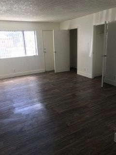 an empty living room with wood floors and a window