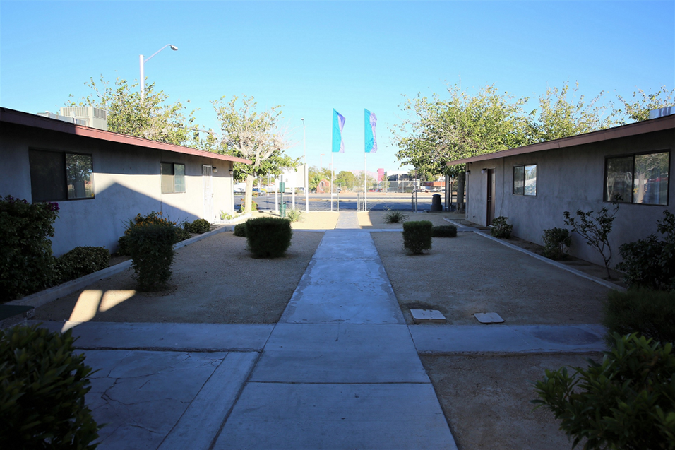an empty walkway between two buildings with trees in the background