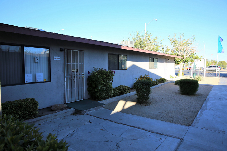the front of a white building with a driveway and a gate