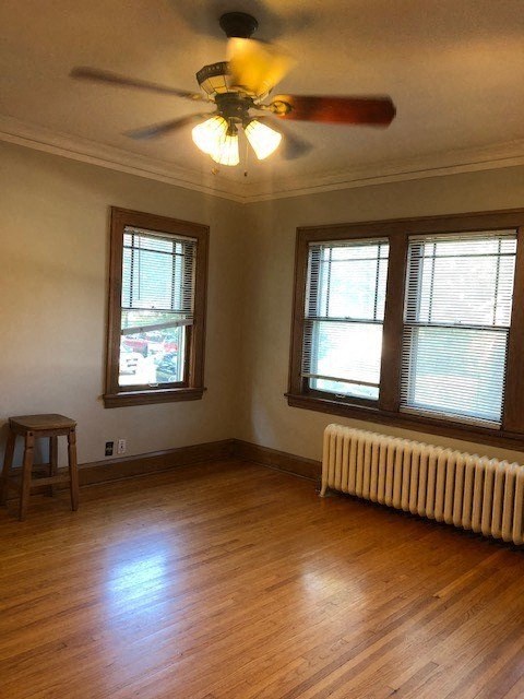 an empty living room with a ceiling fan and two windows