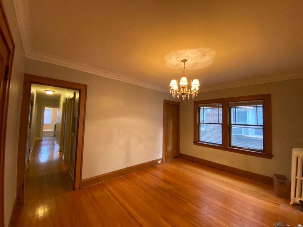 an empty living room with a wood floor and a chandelier