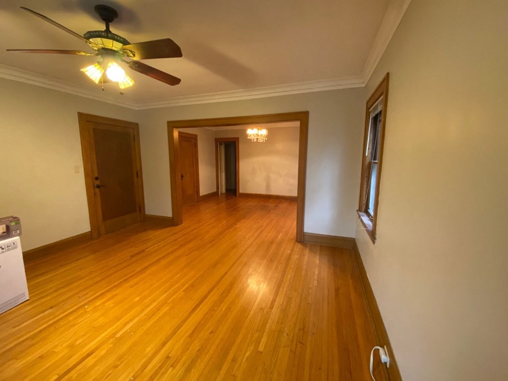 an empty living room with wood floors and a ceiling fan