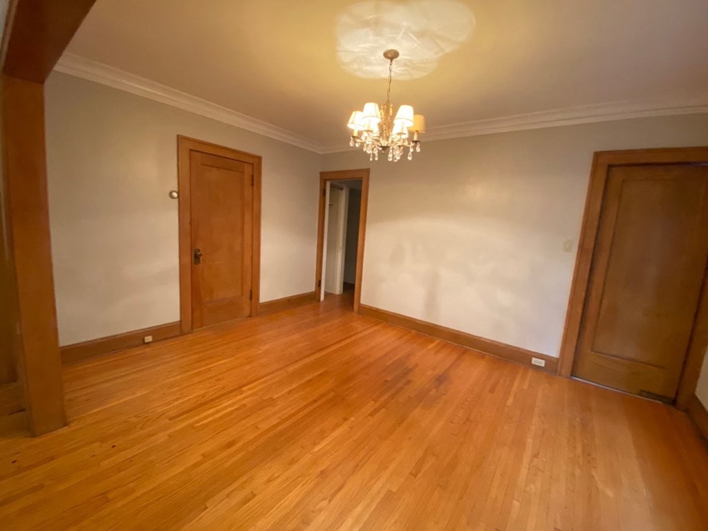 an empty living room with wooden floors and a chandelier