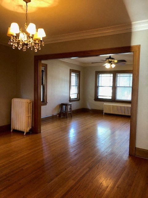 an empty living room with a wooden floor and a chandelier