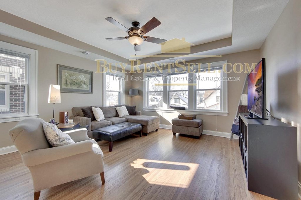 a living room with couches and a tv and a ceiling fan