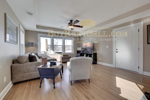 a living room with a couch and a chair and a ceiling fan