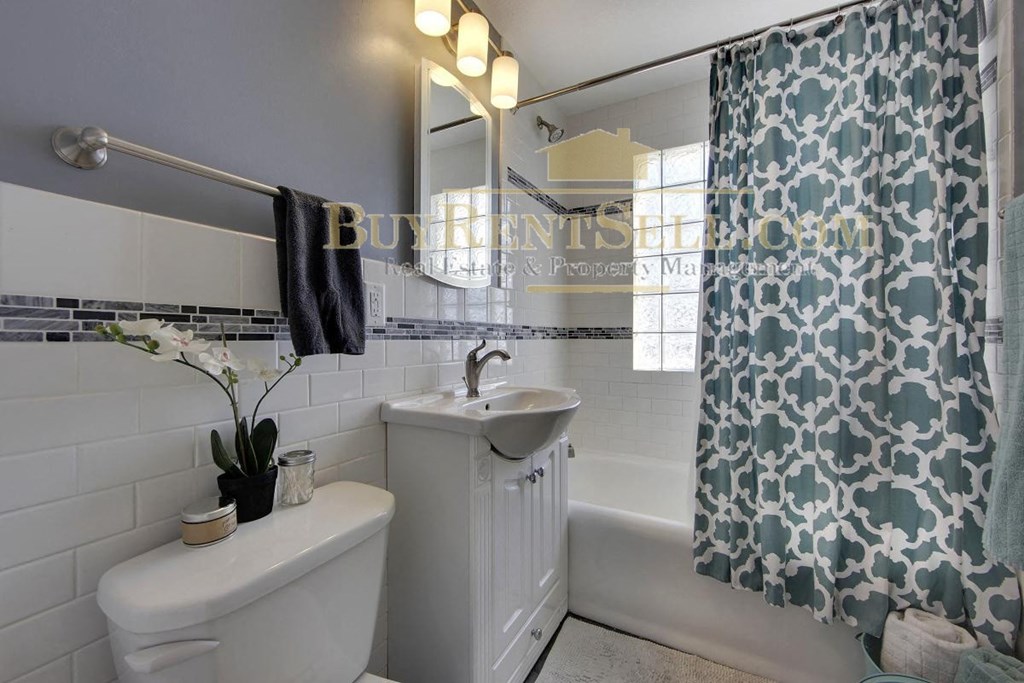 a white bathroom with a shower curtain and a toilet and a sink