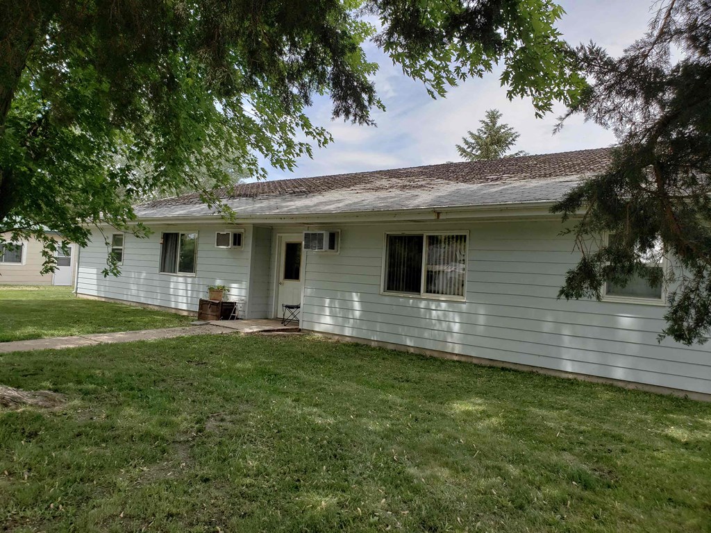 a white house with a lawn and trees