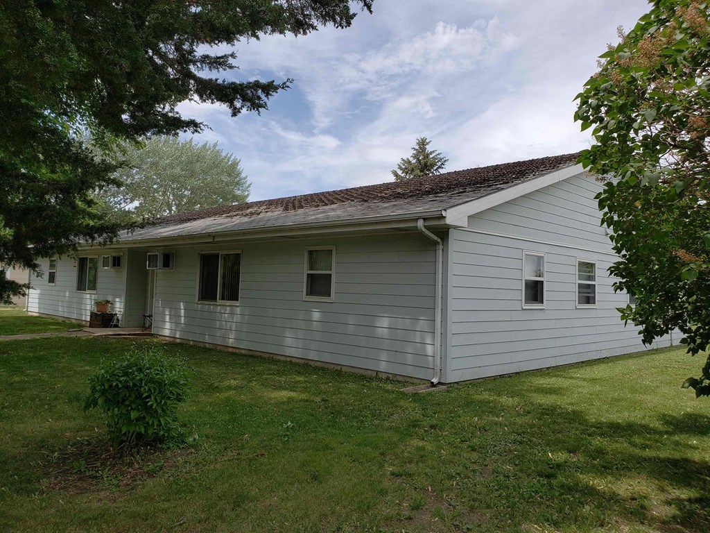 the front of the house with a lawn and trees