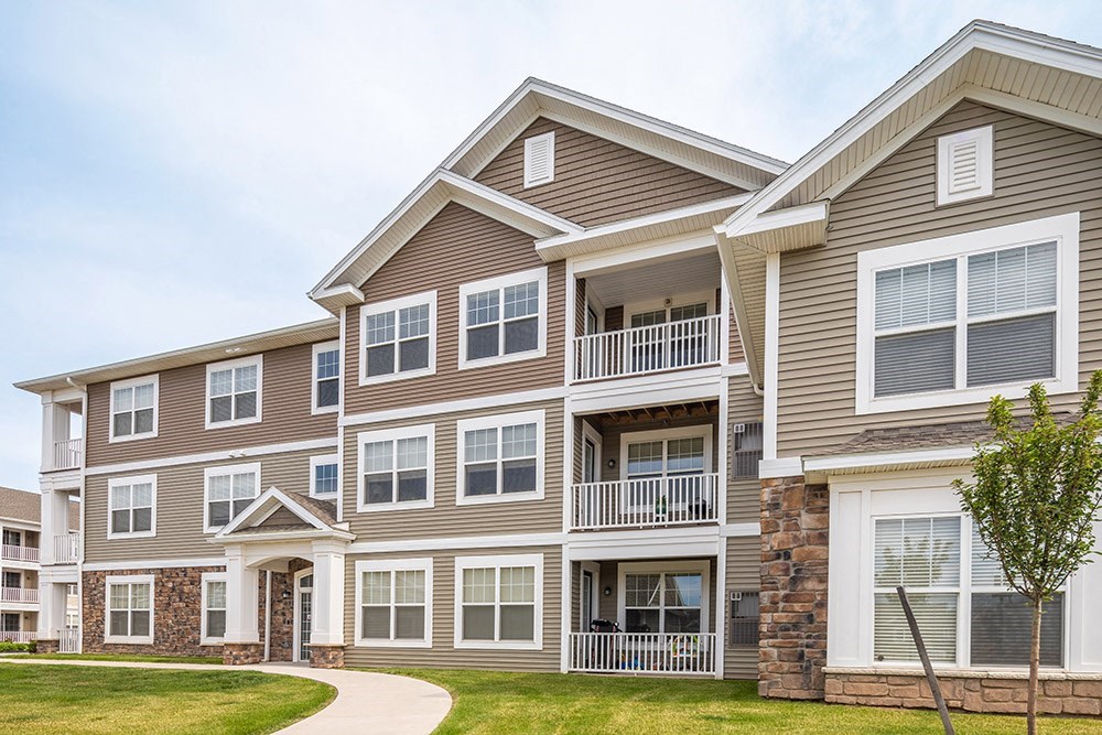 an apartment building with a sidewalk in front of it