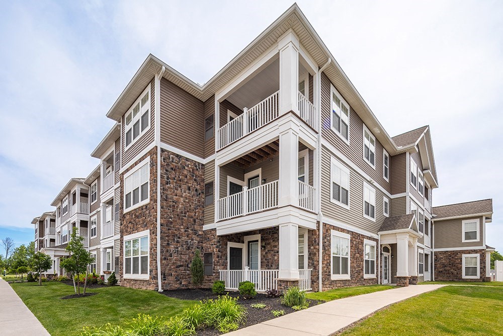 an exterior view of an apartment building with a sidewalk