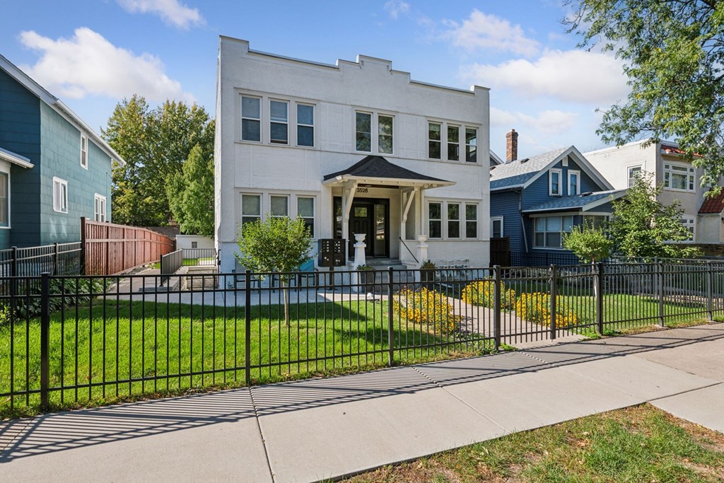 A white house with a black fence in front.