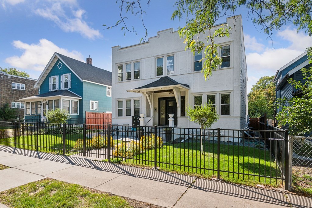 A white house with a black fence in front of it.