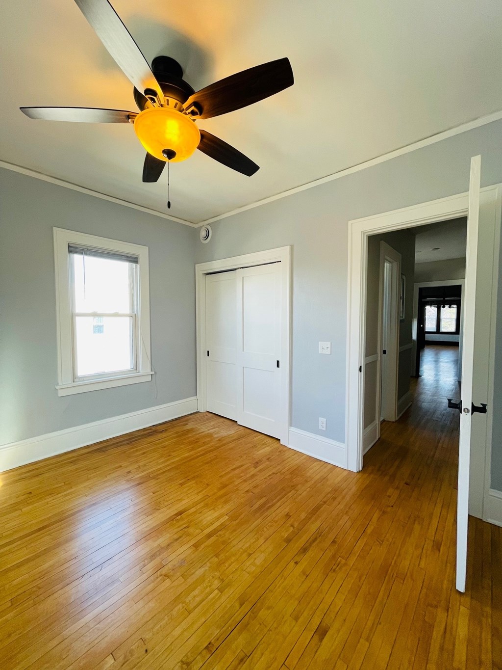 A room with a ceiling fan and wooden floors.