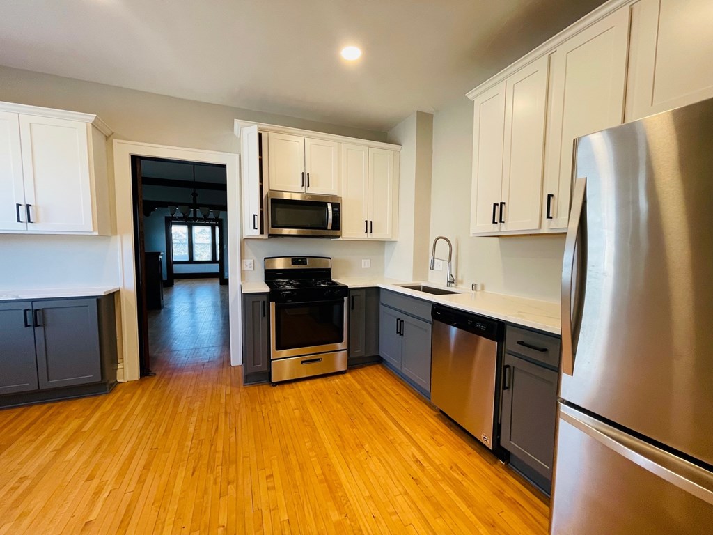 A kitchen with a stainless steel refrigerator and wooden floors.