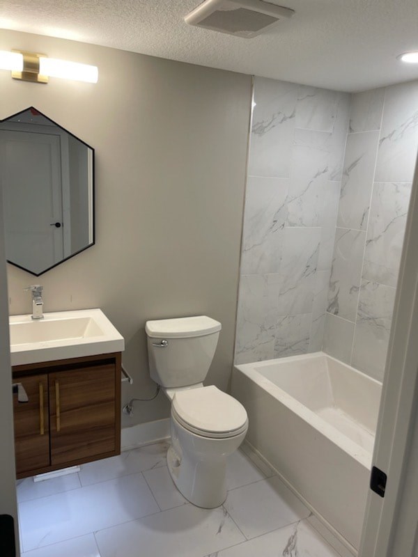 A white toilet sits next to a white sink in a bathroom.