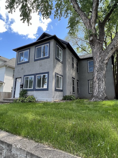 a gray house with a tree in front of it