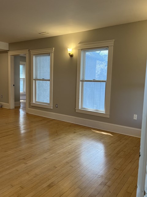 an empty living room with wood floors and two windows