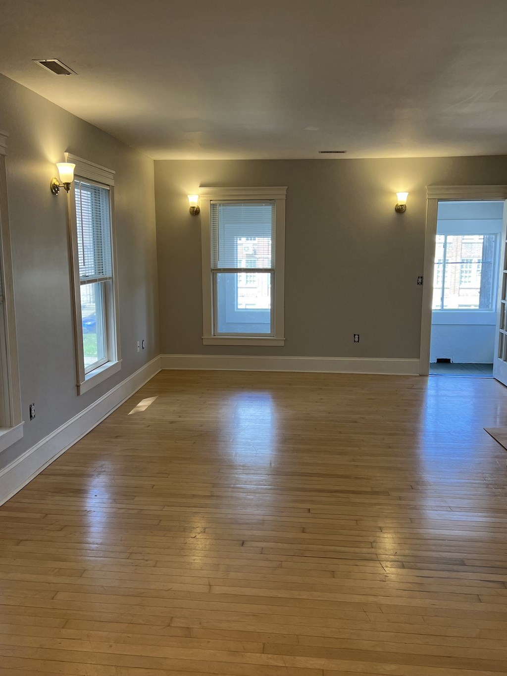 an empty living room with a wooden floor and two windows