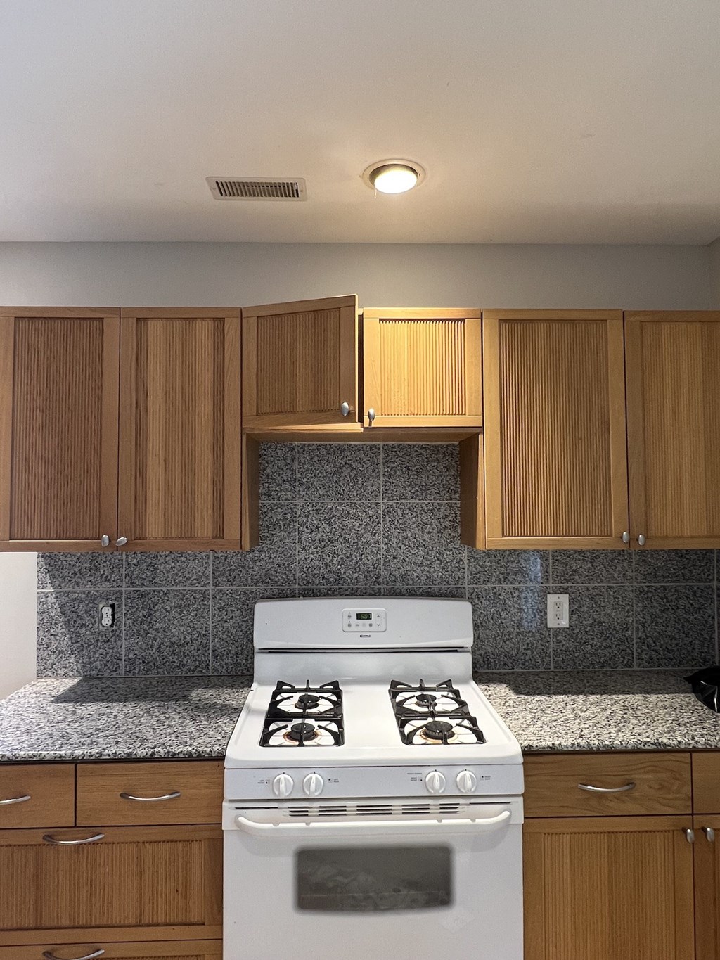 an empty kitchen with a white stove and wooden cabinets