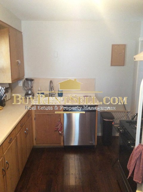 A kitchen with wooden cabinets and a stainless steel dishwasher.