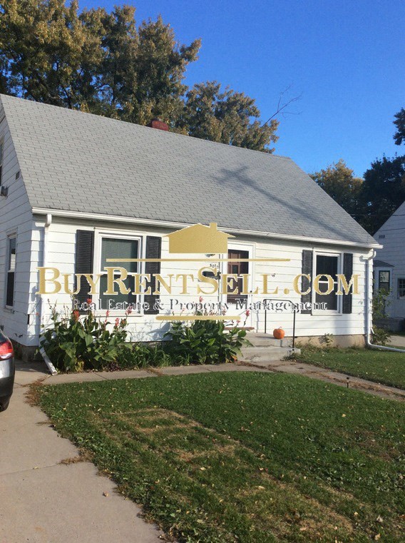 A white house with a sign that says Buy Rent Sell.com.