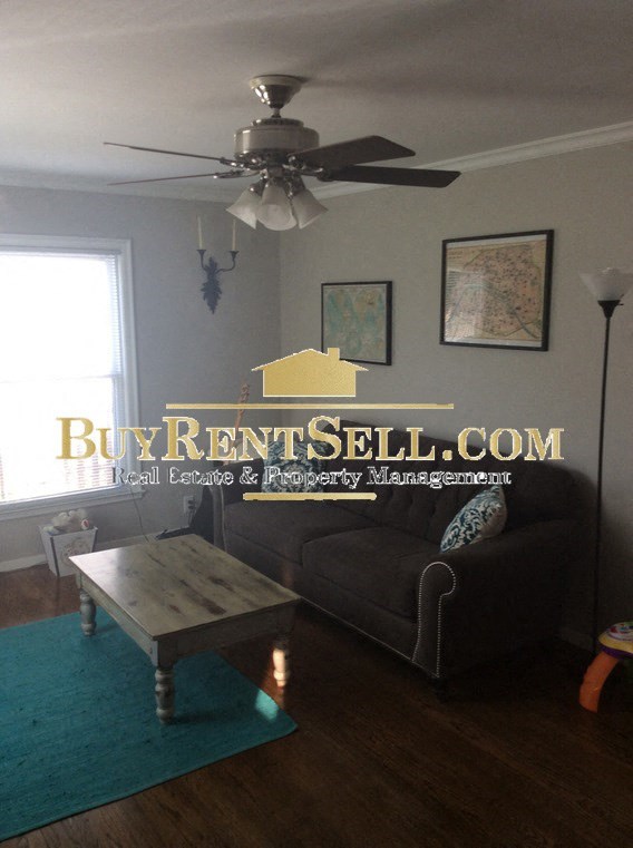 A living room with a BuyRentSell.com logo on the wall.