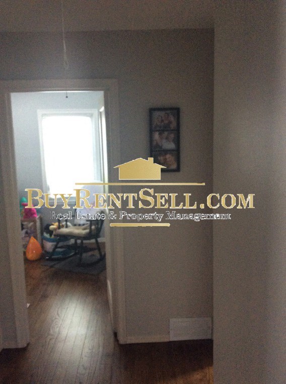 A hallway with a Buy Rent Sell logo on the wall.