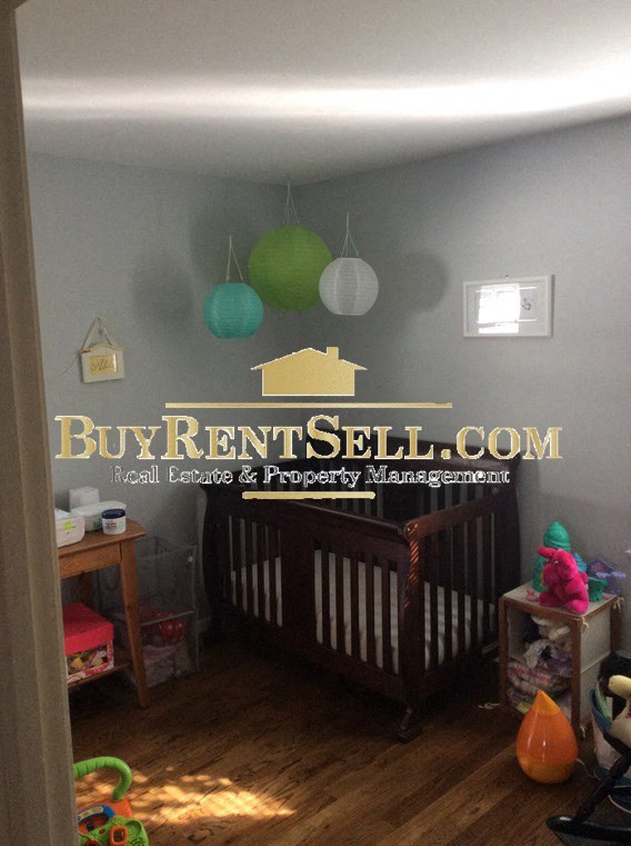 A baby's room with a Buy Rent Sell sign on the wall.
