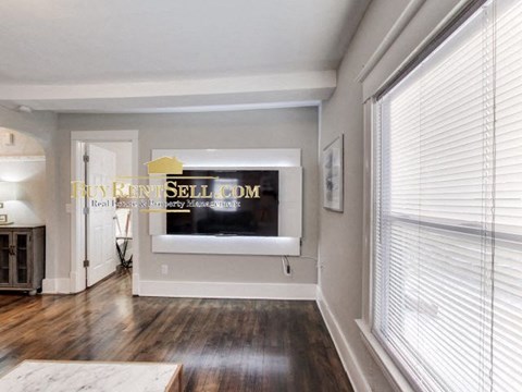 a living room with a large window and a tv on the wall