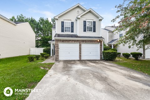 a white house with a white garage door on a driveway