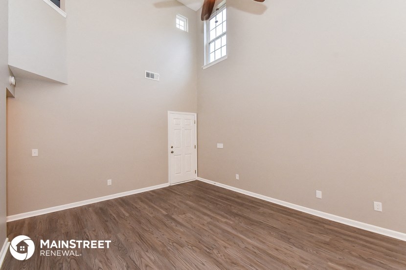 the spacious living room with hardwood flooring and white walls