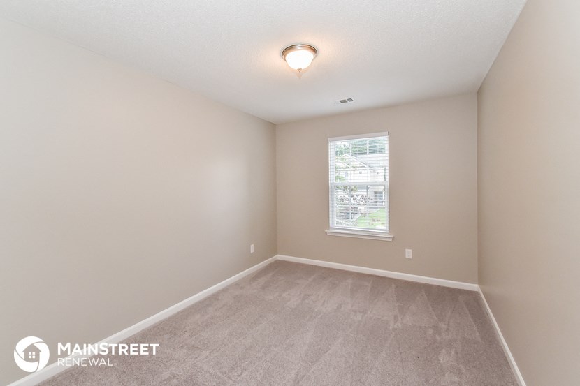 the spacious living room with carpeting and a window