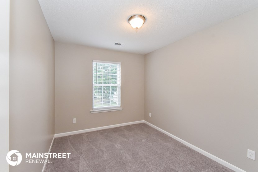 the upstairs bedroom has a carpeted floor and a window