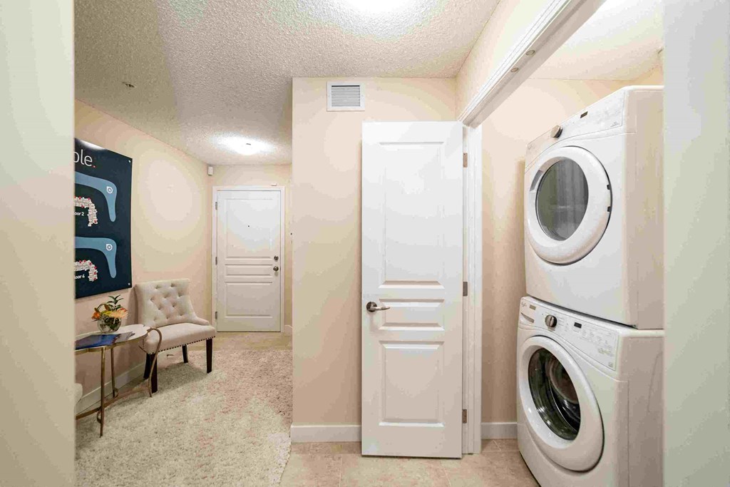 a washer and dryer in a laundry room with a table and chair