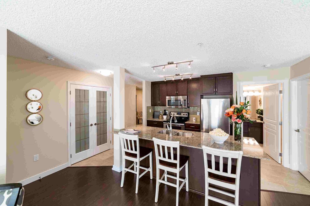 a kitchen with a marble counter top island and white chairs