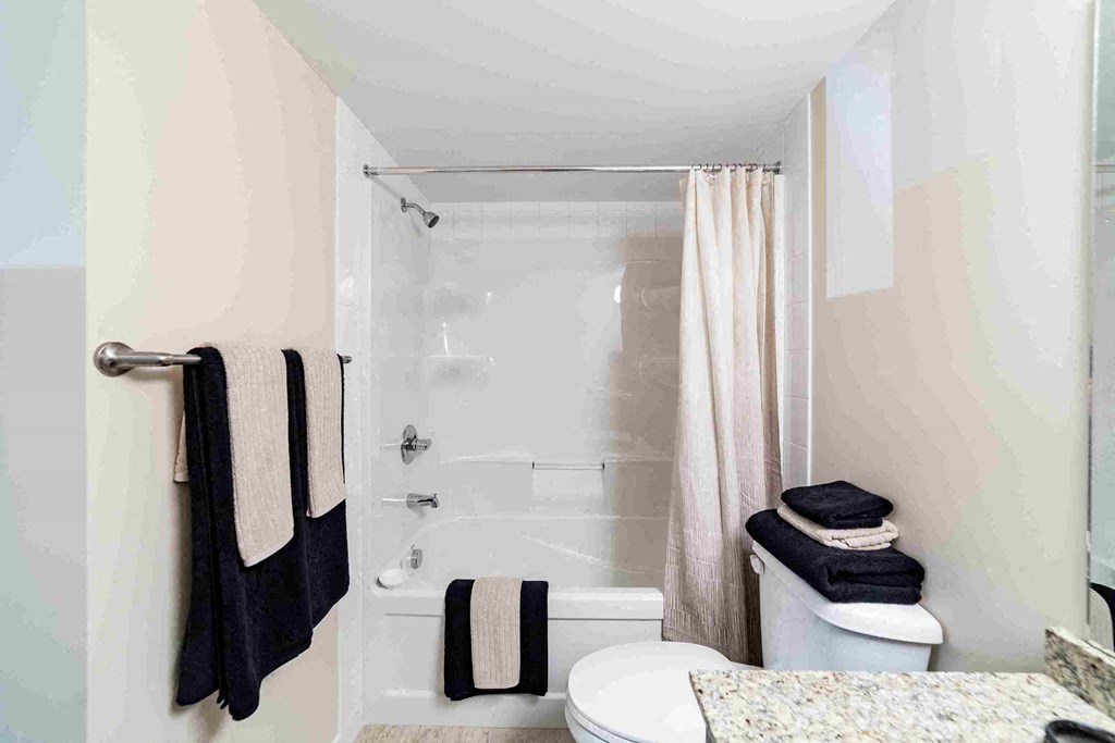 a bathroom with a shower and a toilet and towels