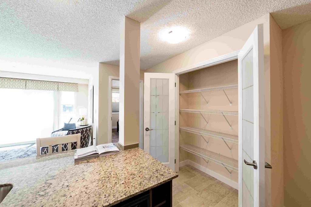 a walk in closet in a master bathroom with a granite counter top