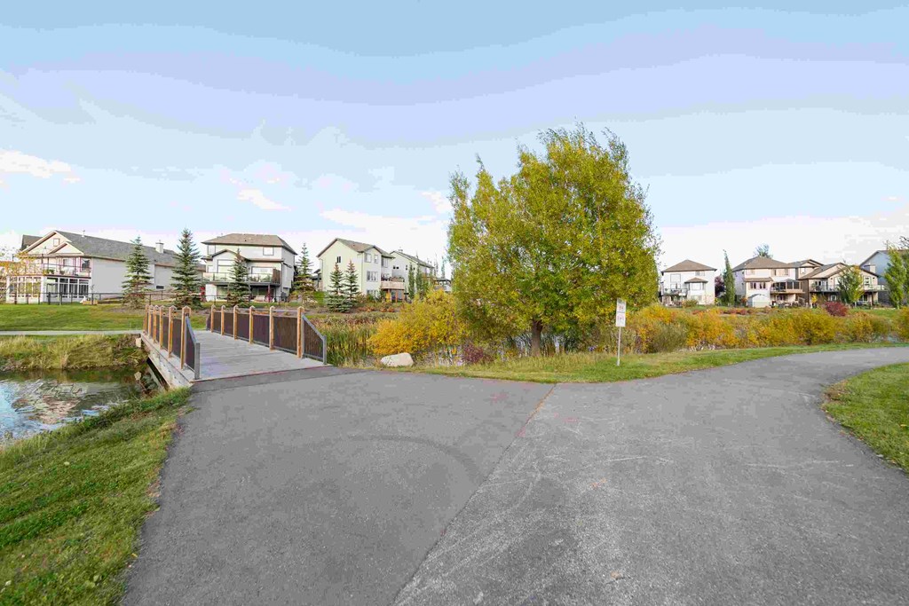 a paved pathway with houses on the other side of the water