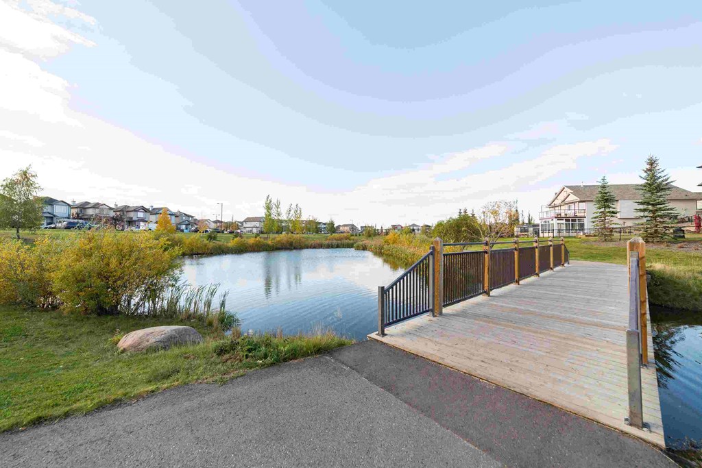 a bridge over a pond with houses in the background