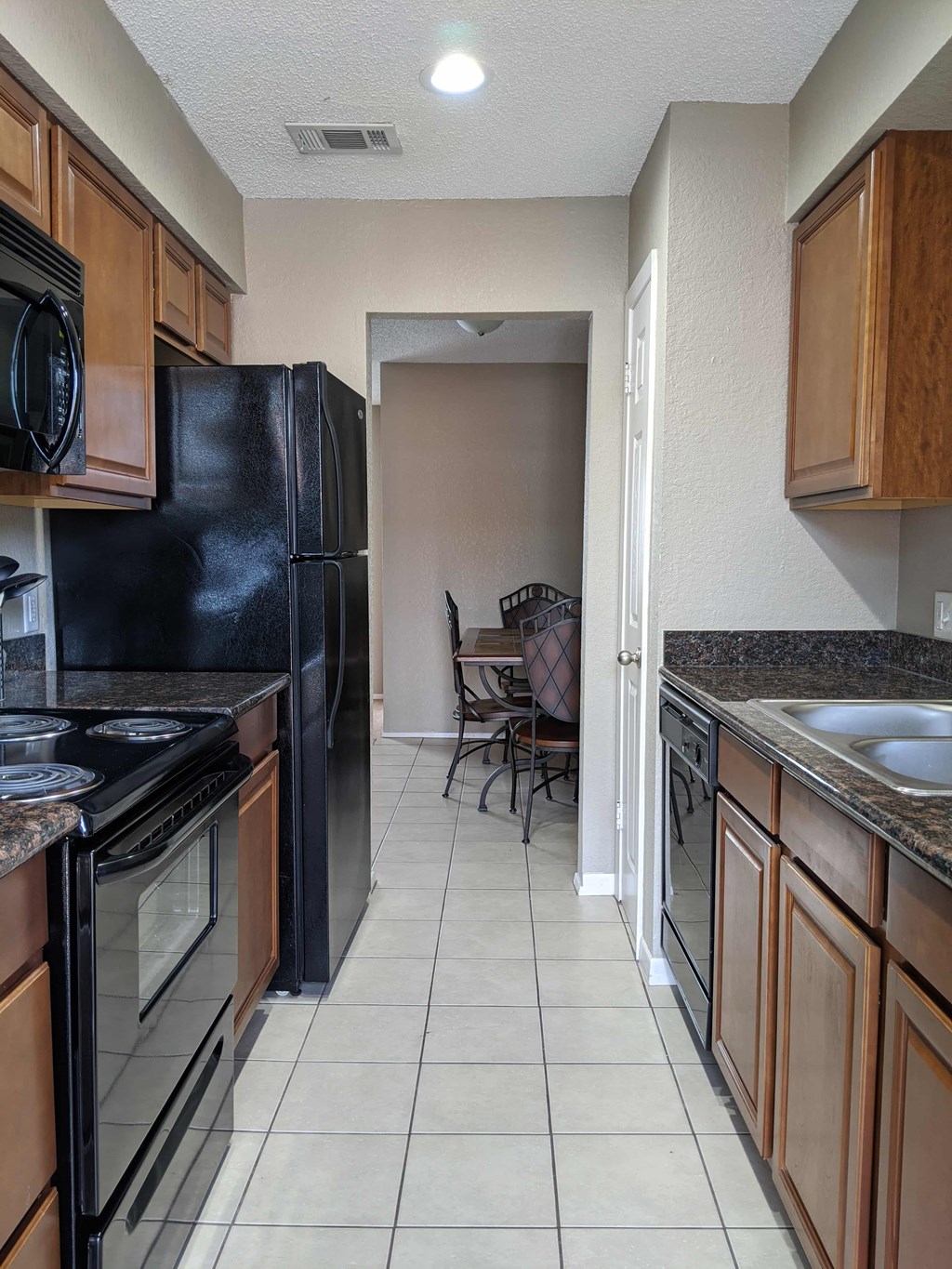 A kitchen with black appliances and brown cabinets.