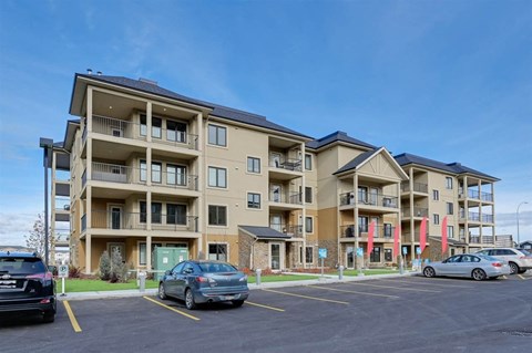 a parking lot with cars in front of an apartment building
