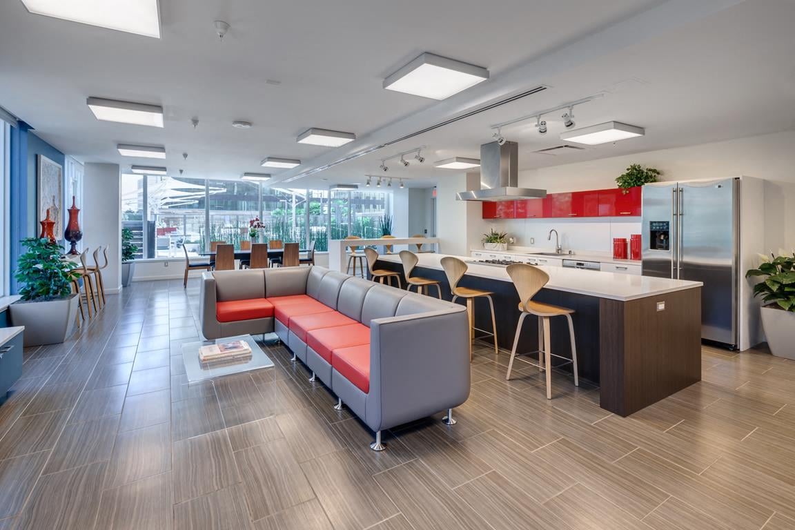 A modern open plan office and kitchen area with a long table and chairs.