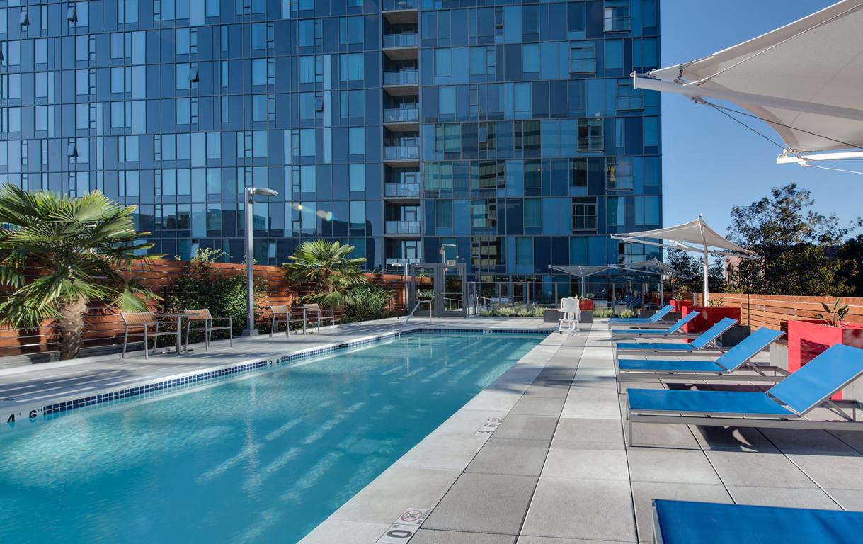 Pet Friendly Apartments in Downtown San Jose, CA - One South Market Swimming Pool with Lounge Chairs, Lush Landscaping, and Table Seating